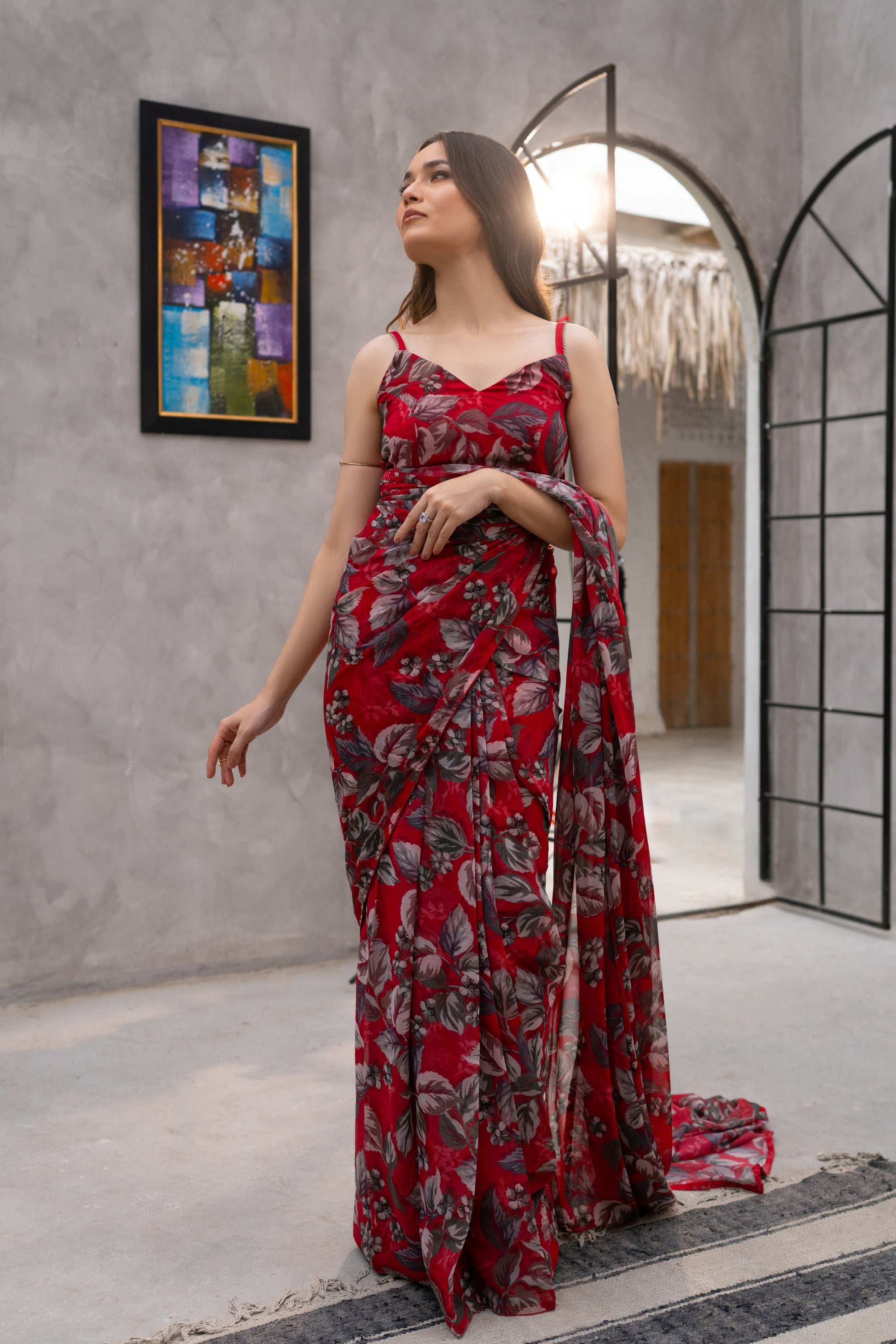 Woman in a red floral dress standing in a modern interior setting.