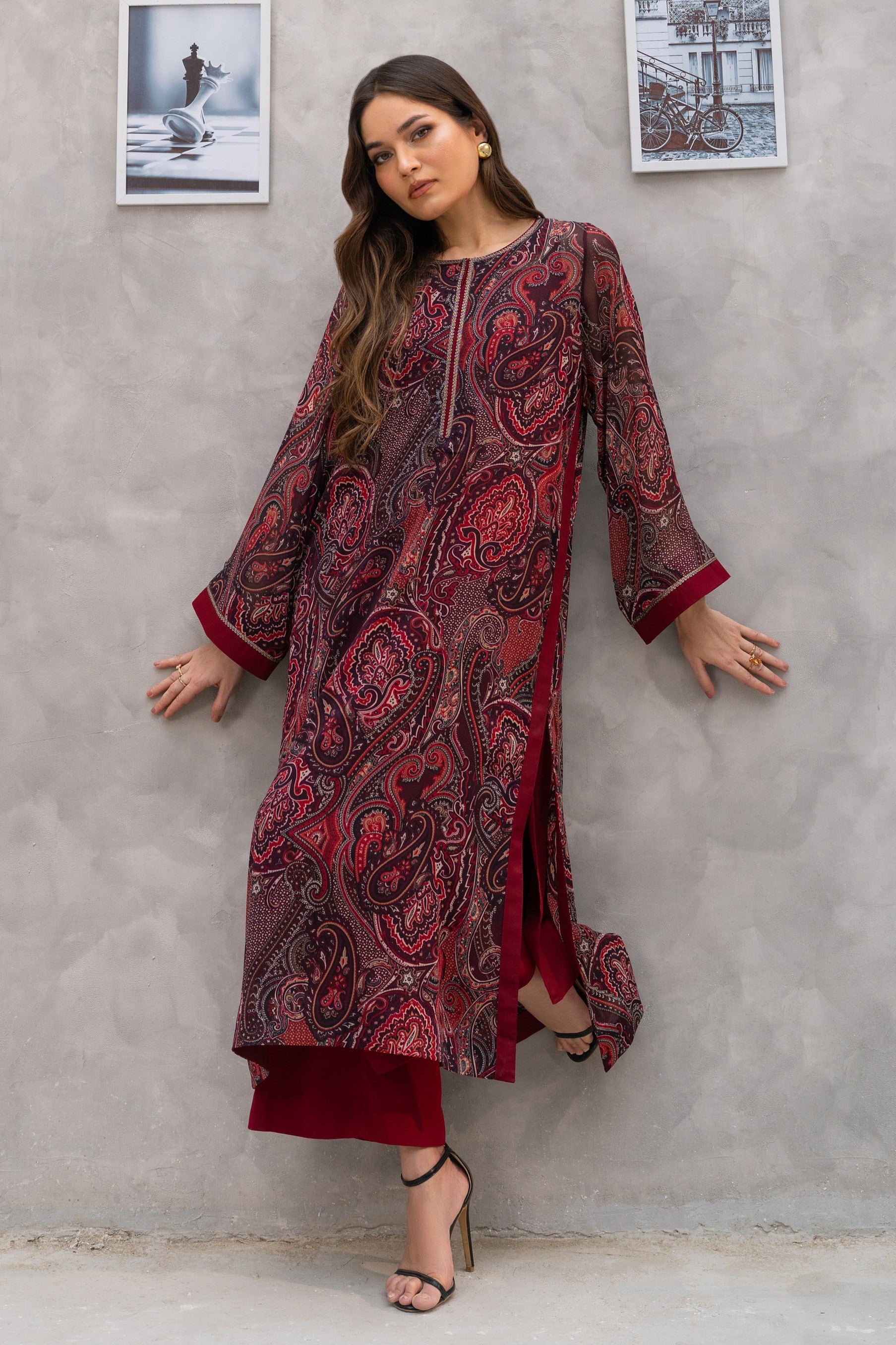 Woman wearing a red and black patterned dress against a gray wall.
